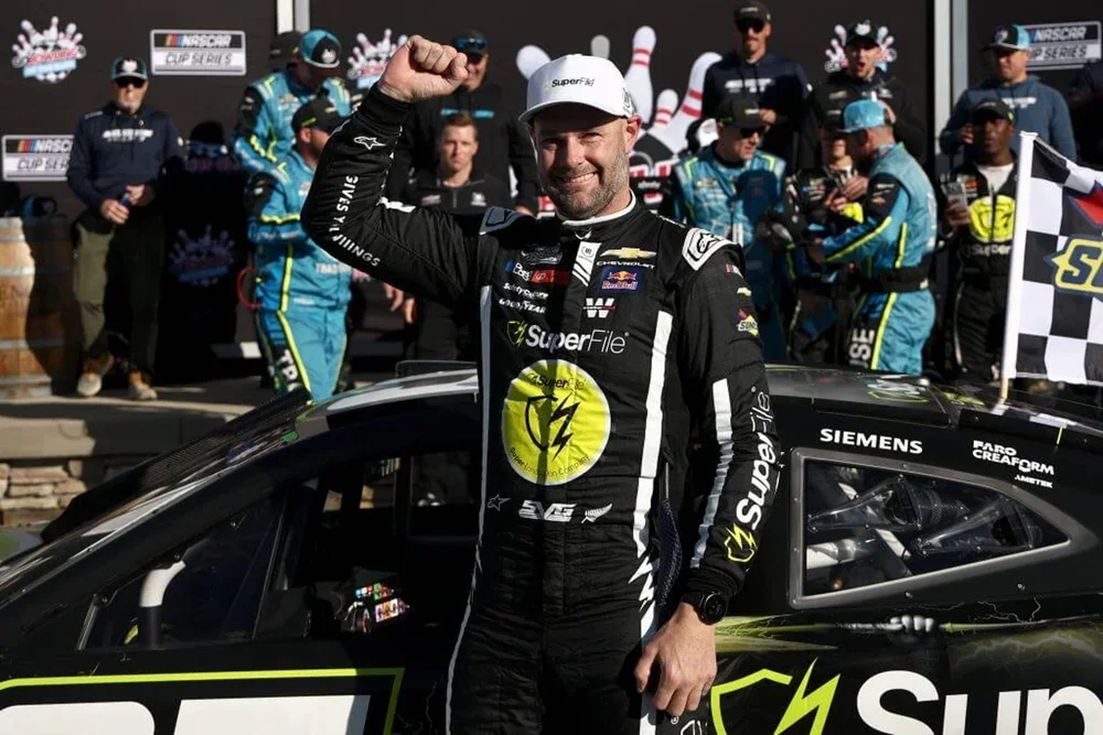 Shane van Gisbergen, in a black racing suit, raises a fist in the air in celebration of Sunday's win.